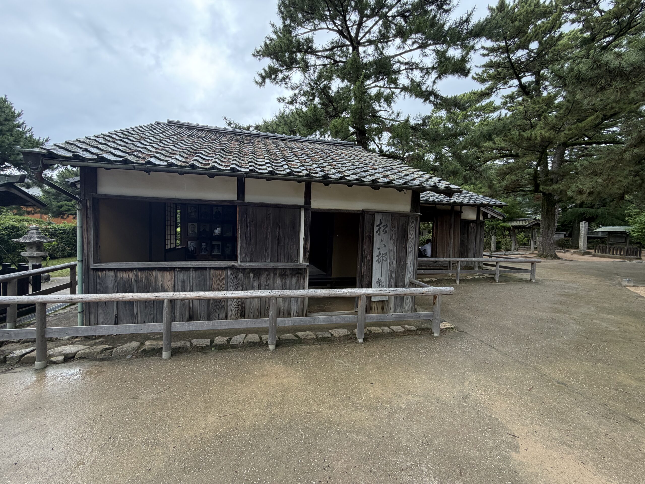 松に囲まれた瓦屋根の木造建物
